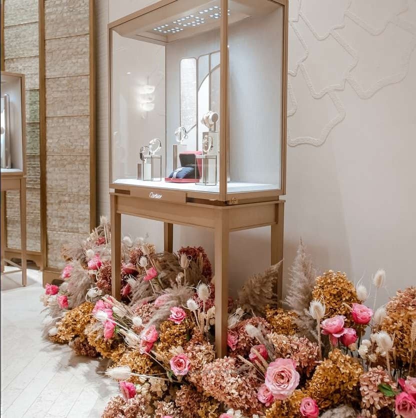 Pink roses and dried flowers beneath a glass display case