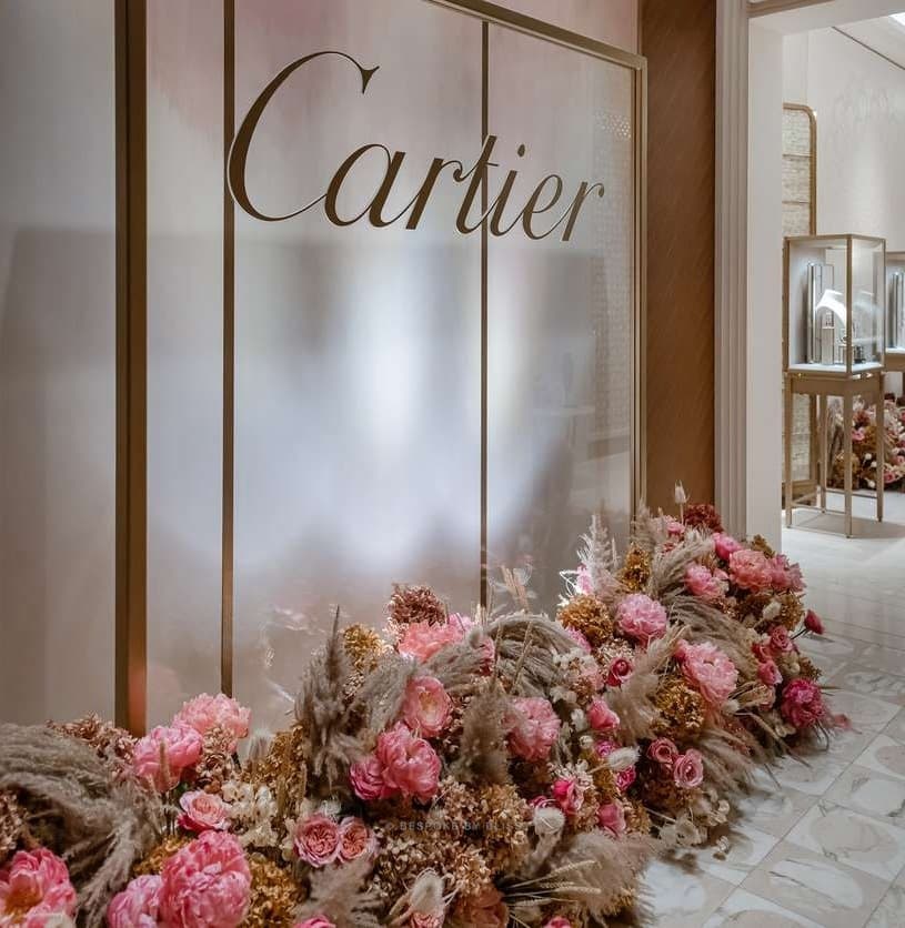 Pink and dried flowers along the foot of a frosted glass wall in a boutique