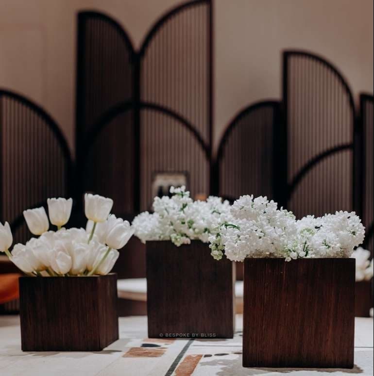 White tulips and lilac in wooden boxes in front of a fluted screen