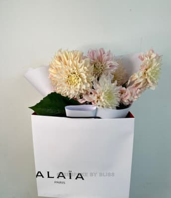 Cream and blush dahlias in a white paper bag