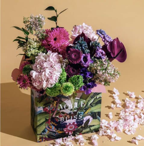 A printed botanical gift box topped with a large mixed flower arrangement
